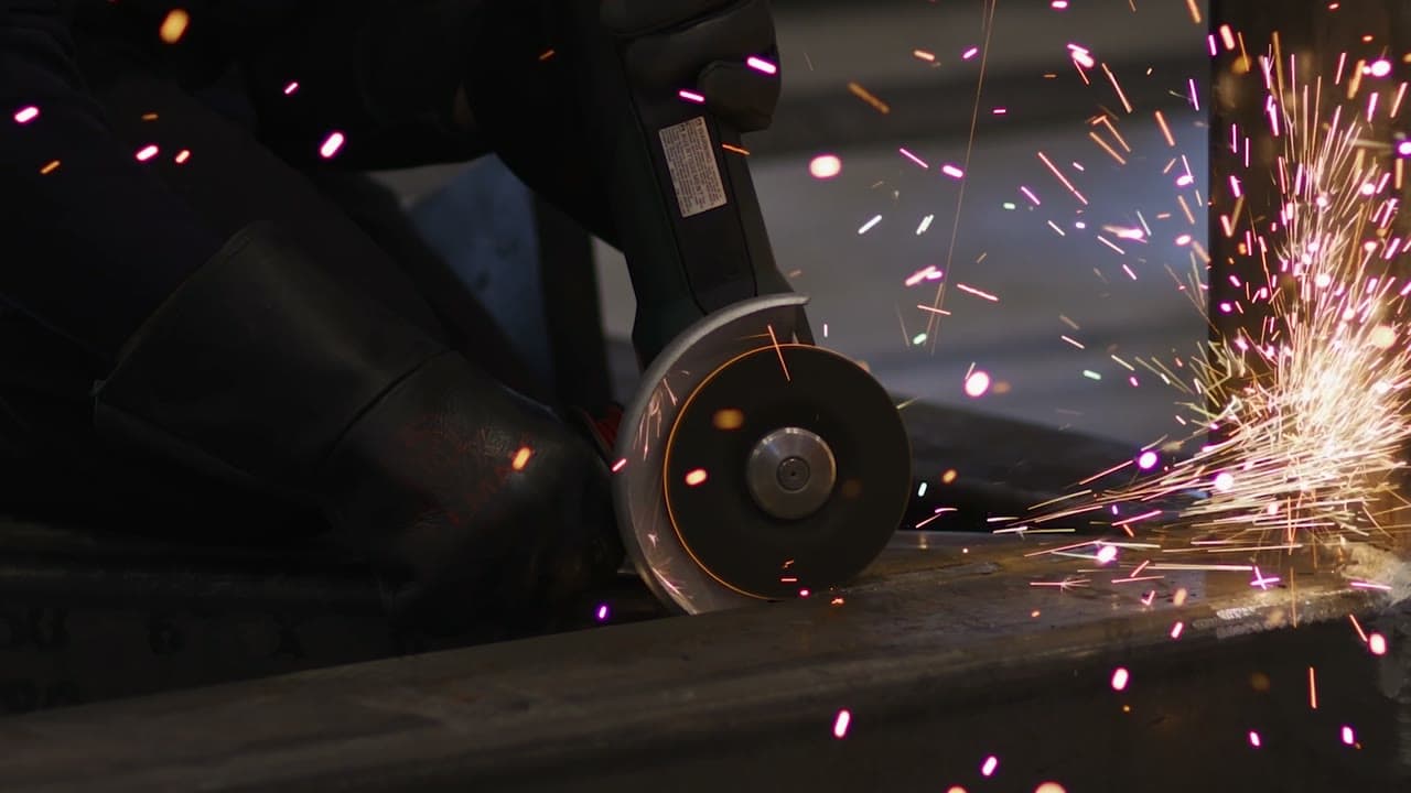 Sparks from a grinder, the reactor vessel in a sling, and the Aalo team on site at sunset.